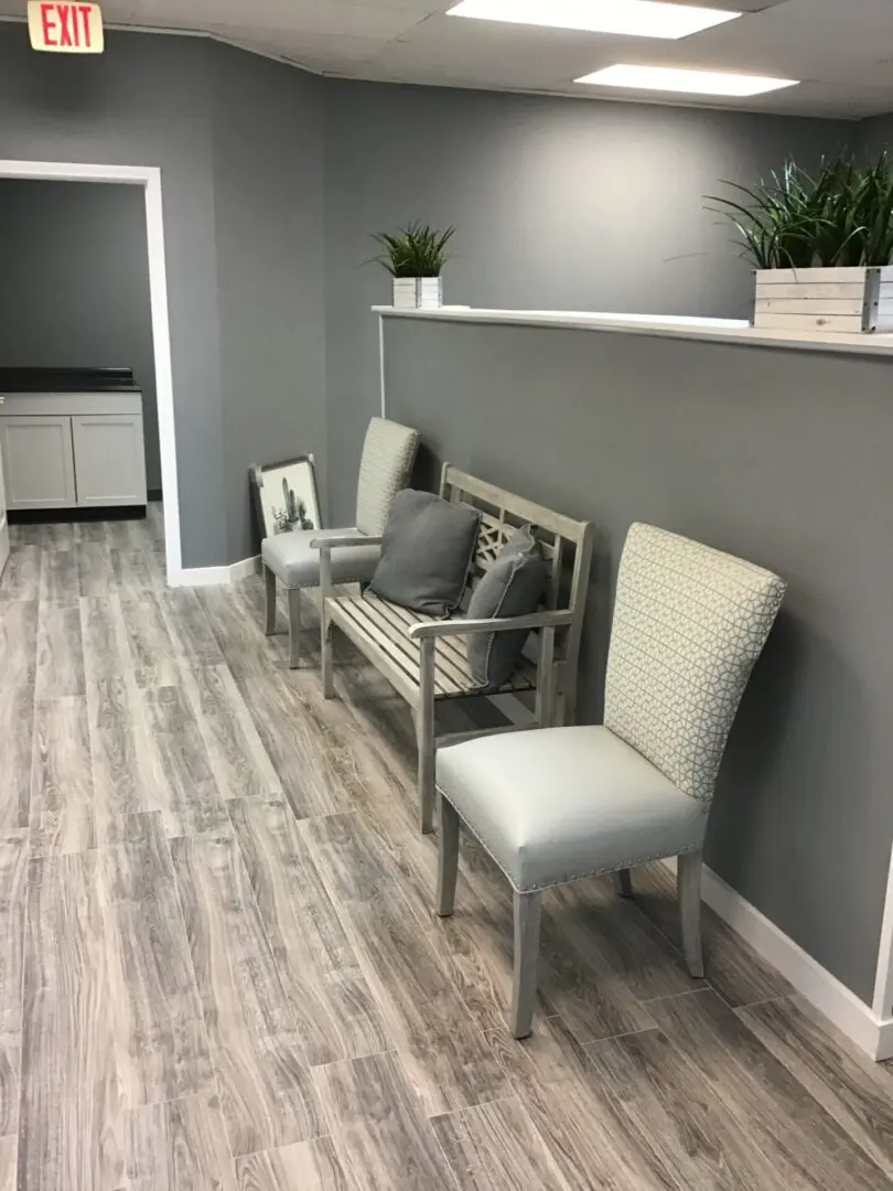 A bench and two chairs in the middle of a room.